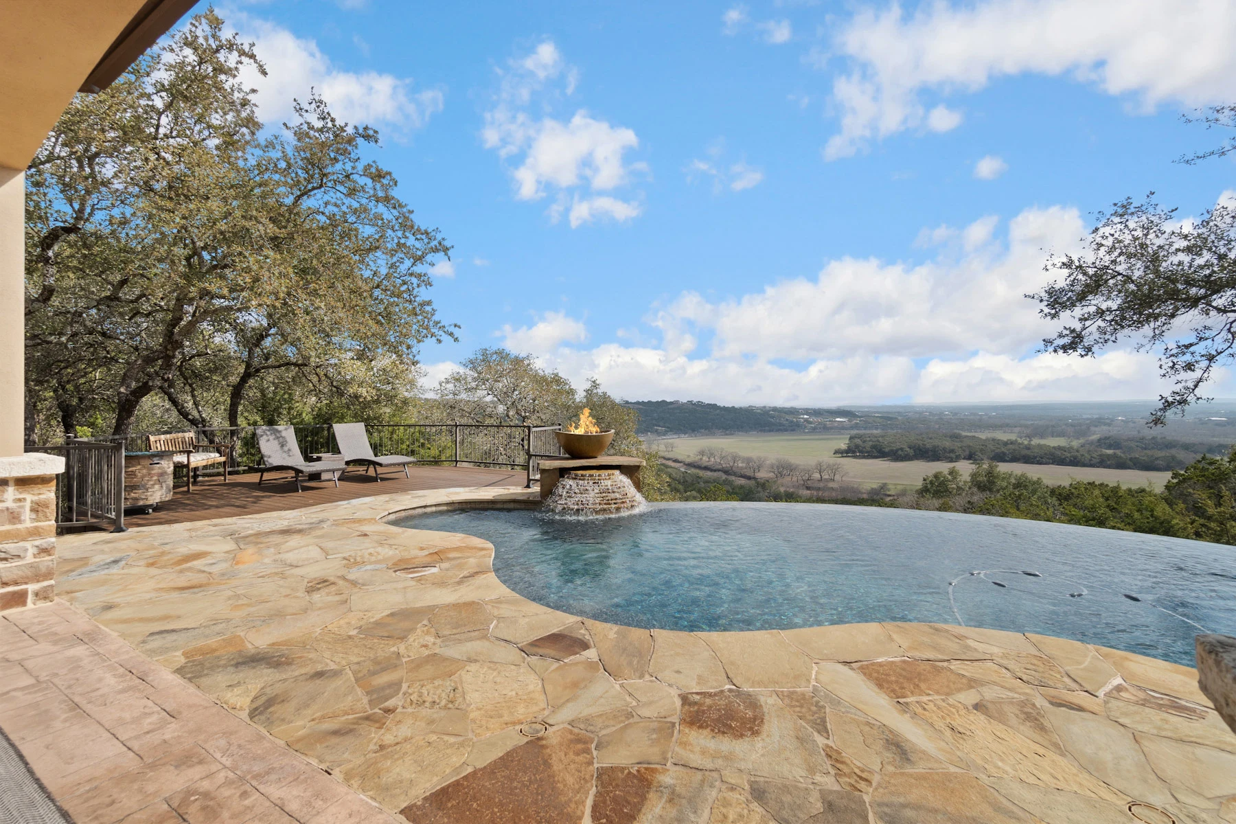 Residential swimming pool with a stone deck and surrounding outdoor seating