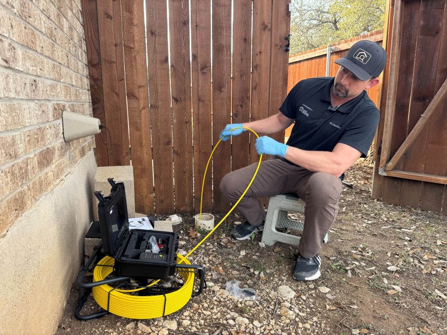 Eaton Bates feeding a sewer camera through an accessible cleanout