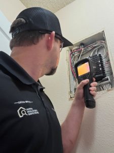 Home inspector Eaton Bates using a thermal imager at an electrical panel in Leander