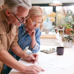 Mature,Couple,Reviewing,And,Signing,Domestic,Finances,And,Investment,Paperwork