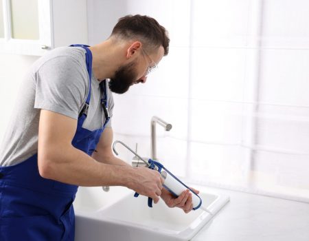 Worker,With,Caulking,Gun,Sealing,Kitchen,Sink,Indoors